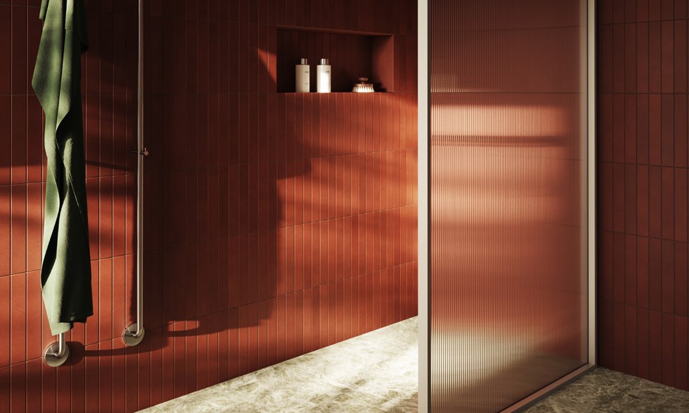 Moderne baderom med smale røde fliser, rillet glassvegg og natursteinsgulv.