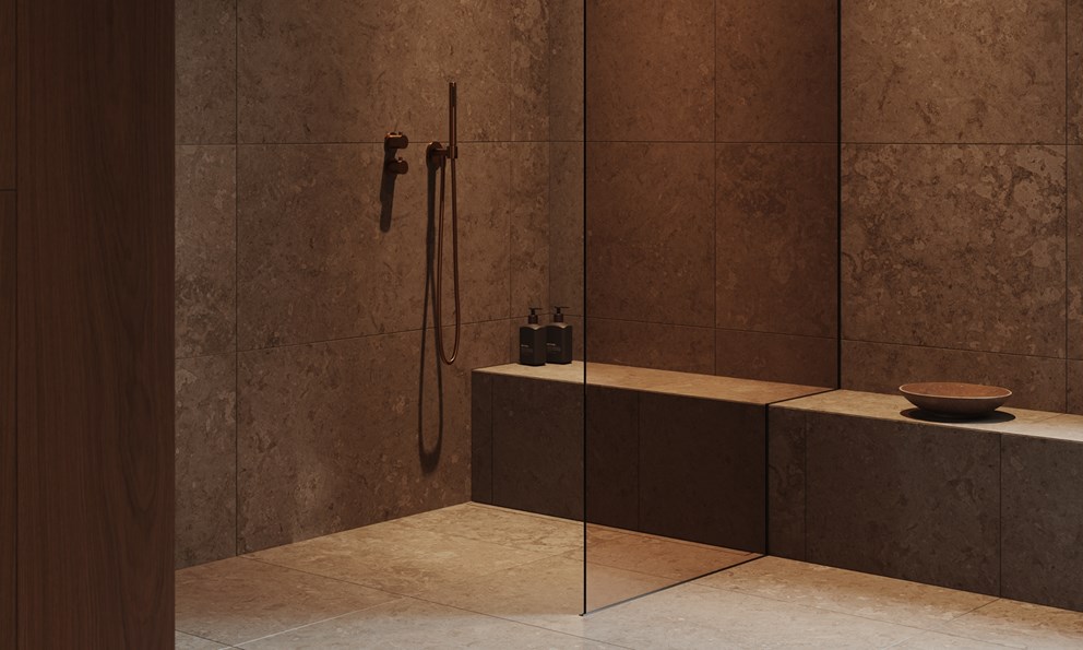 Moderne dusjsone med mørke naturmaterialer, glassvegg og armatur i bronse.