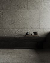 Naturstein i varme toner kombinert med mørkt treverk og taktile detaljer – et tydelig uttrykk for materialfokus i baderomstrender 2026.