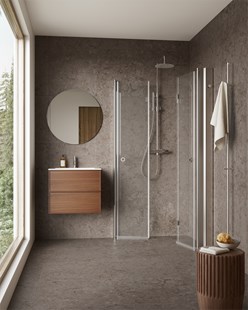 Lite baderom med mørk kalkstein, innfellbare dusjdører i glass og vegghengt servantskap i tre.