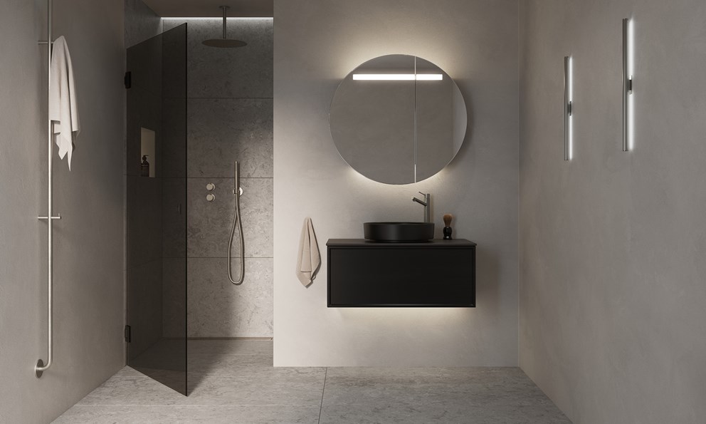 Moderne baderom med sort servantskap, rund servant, stort speil og dusjsone i grå naturstein.