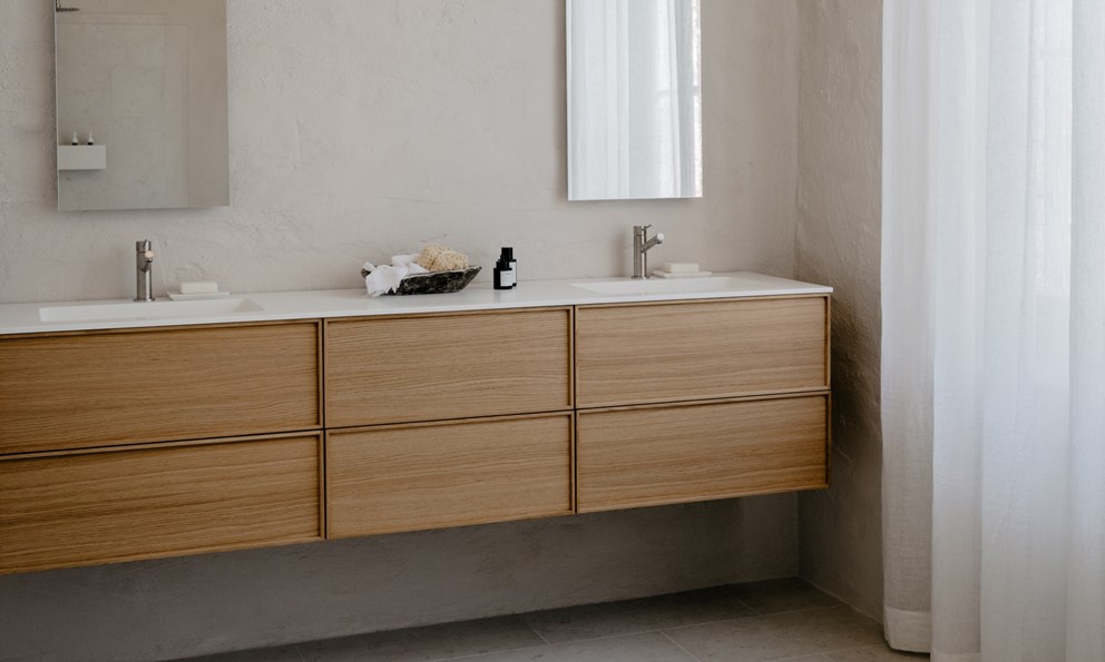 Lyst nordisk baderom med servantskap i tre, dobbelt servant og minimalistiske detaljer.