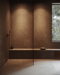 Moderne dusjsone i naturstein med minimalistisk glassvegg, dusjbenk og varmt innfelt lys.