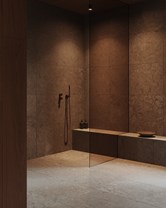 Sømløs dusjsone i naturstein med integrert sittebenk og varme materialer – et uttrykk for baderomstrender og dusjtrender i 2026.